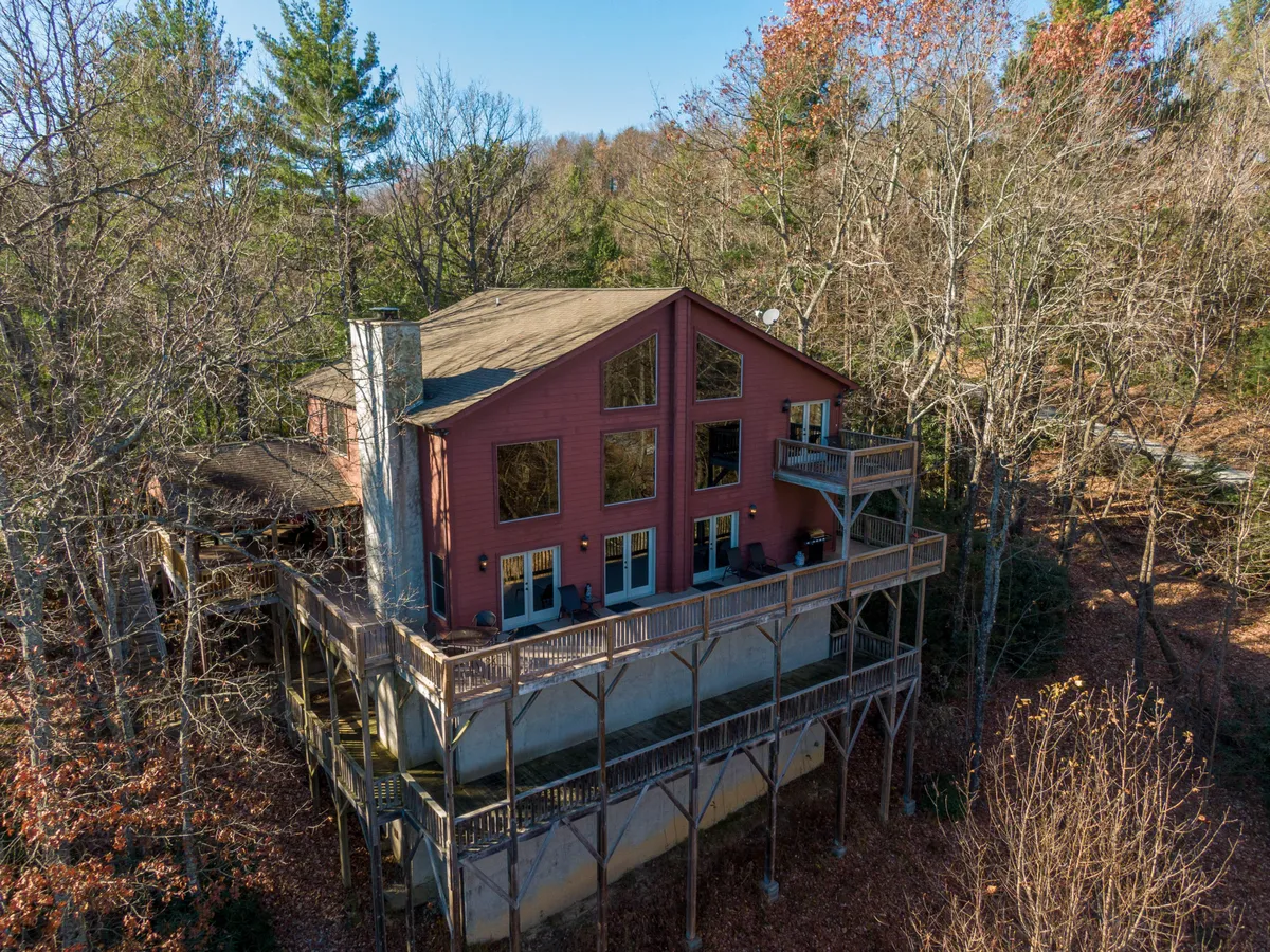 The exterior of the home featuring large windows and a sizable balcony overlooking the surrounding forested landscape. The scene exudes tranquility while hinting at opportunities for enjoying nature views, morning coffee, and family gatherings in the fresh air.